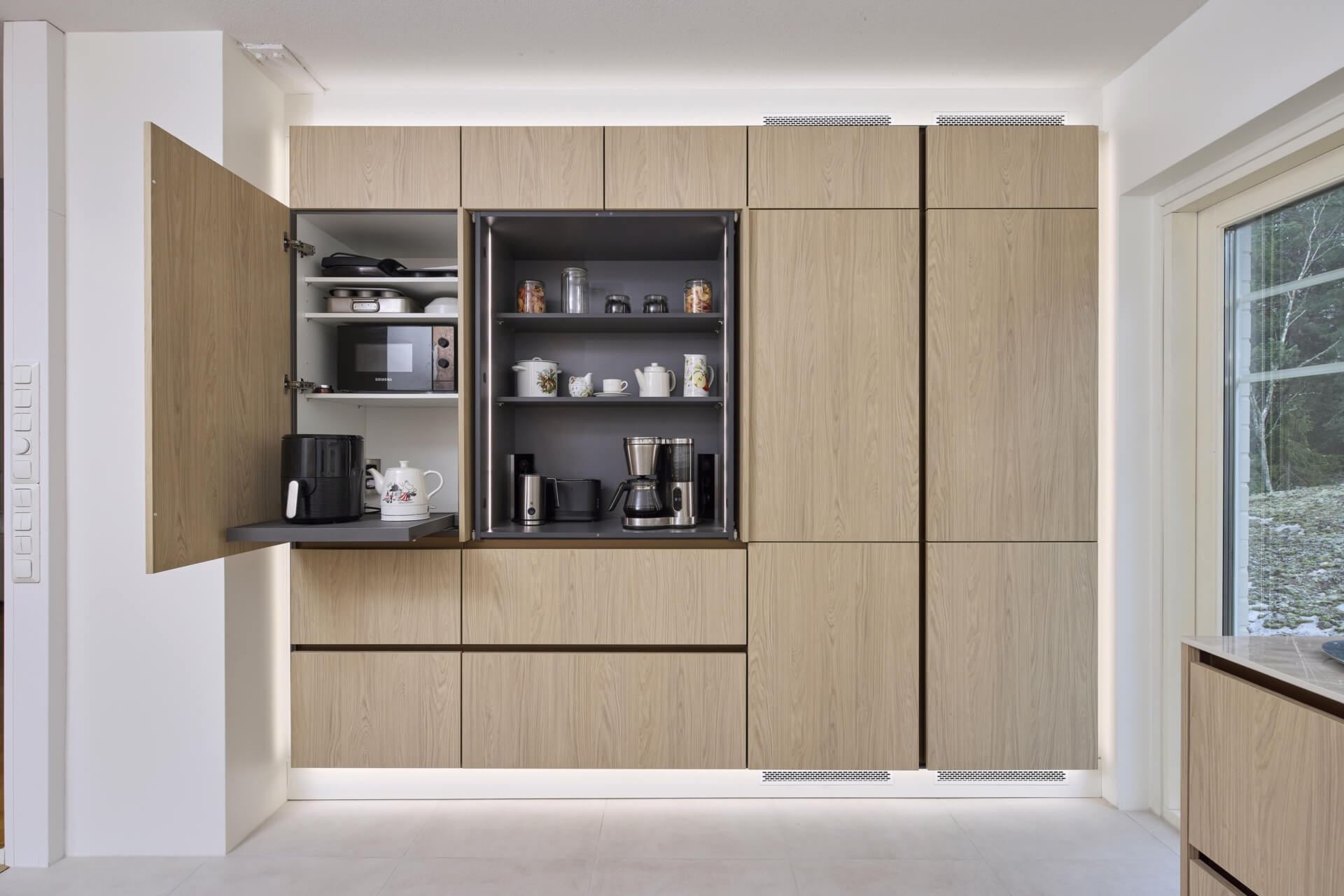 Omakotitalon keittiöremontissa tila uusittiin katosta lattiaan. Vaalea laattalattia korostaa kaappiseinän upeaa valoraamia.